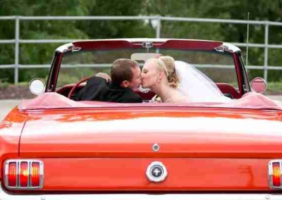Contemporary Wedding Venues | Just Married Couple Kissing in Red Mustang
